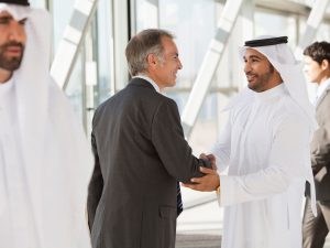 Businessman in suit shaking hands with businessman in kaffiyeh